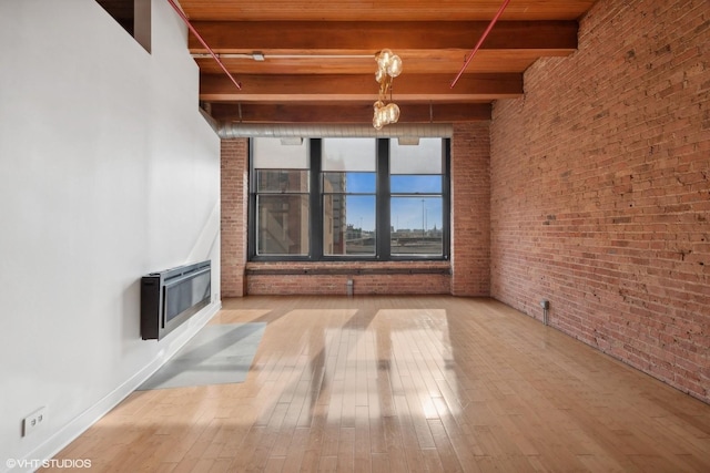 unfurnished living room with heating unit, beam ceiling, a high ceiling, and light wood-type flooring