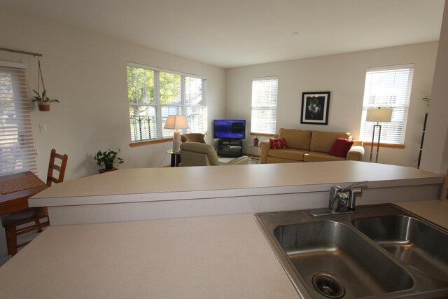 kitchen with light brown cabinetry, sink, kitchen peninsula, and white appliances