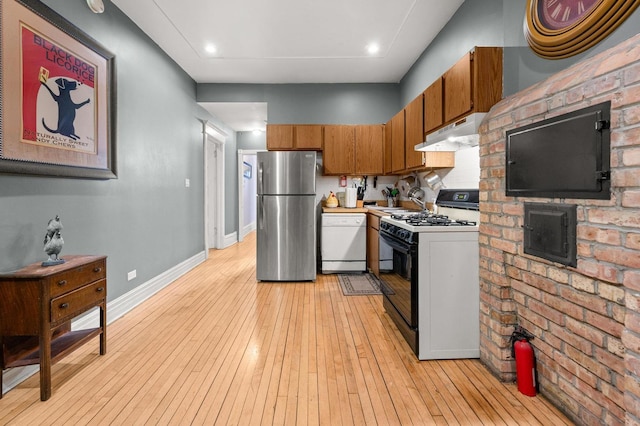 kitchen with gas range oven, dishwasher, stainless steel fridge, and light hardwood / wood-style floors