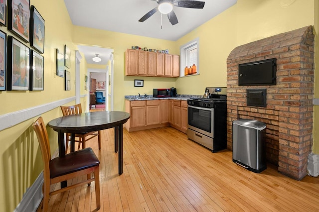 kitchen featuring stainless steel gas range, light hardwood / wood-style floors, light brown cabinets, and ceiling fan