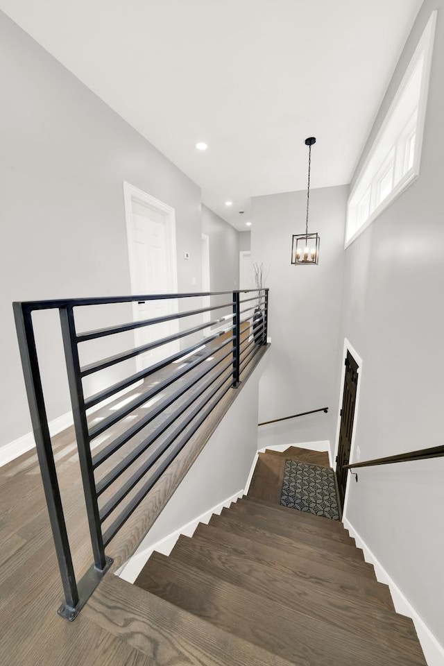 stairs featuring wood-type flooring and a notable chandelier