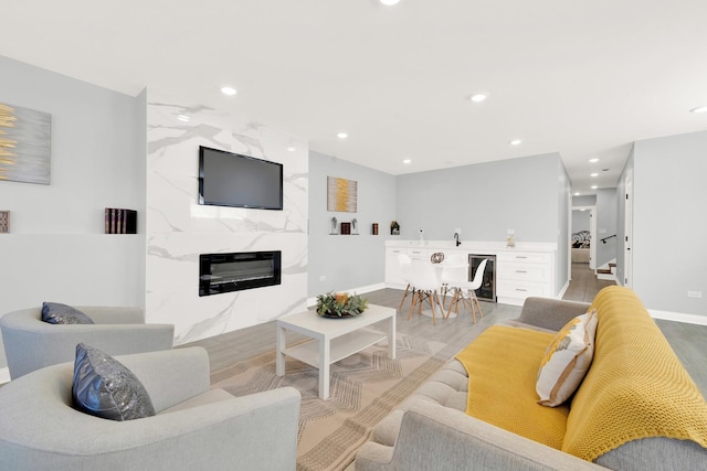 living room featuring light hardwood / wood-style floors, beverage cooler, and a high end fireplace