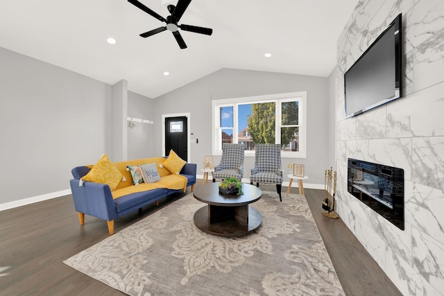 living room featuring ceiling fan, dark hardwood / wood-style floors, a tile fireplace, and lofted ceiling