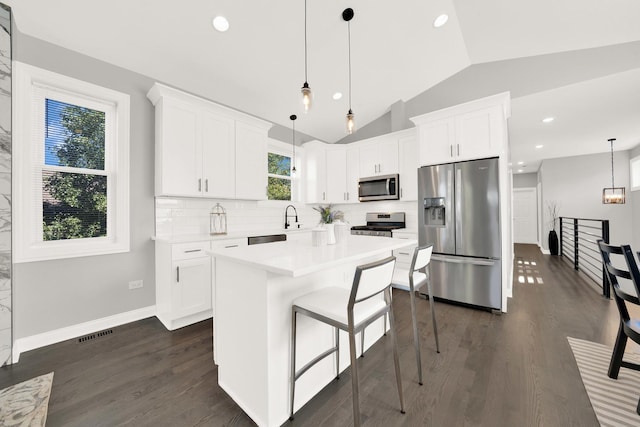 kitchen featuring hanging light fixtures, appliances with stainless steel finishes, white cabinetry, and a center island