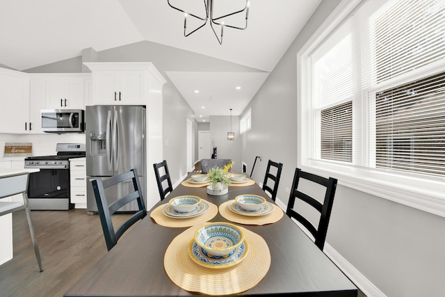 dining room with an inviting chandelier, dark hardwood / wood-style flooring, and lofted ceiling