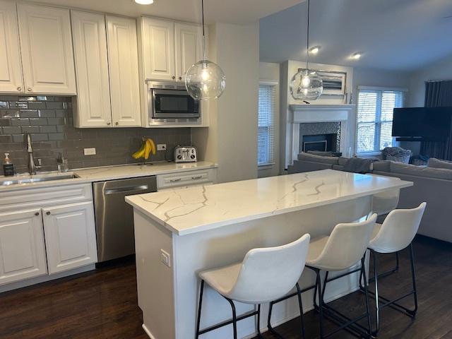 kitchen with pendant lighting, sink, a breakfast bar area, appliances with stainless steel finishes, and white cabinets