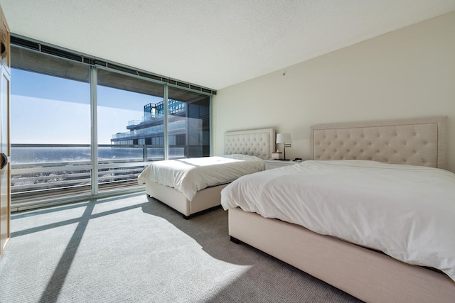 carpeted bedroom with multiple windows, floor to ceiling windows, a textured ceiling, and a water view