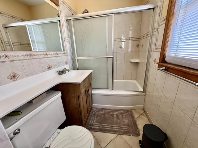 full bathroom featuring toilet, bath / shower combo with glass door, tile walls, vanity, and tile patterned floors