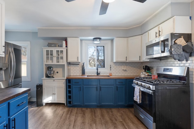 kitchen featuring appliances with stainless steel finishes, blue cabinetry, sink, and wooden counters