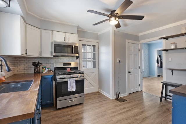 kitchen featuring wood counters, appliances with stainless steel finishes, blue cabinetry, white cabinets, and sink