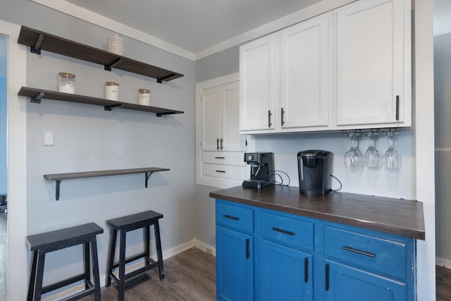 kitchen with blue cabinets, crown molding, dark wood-type flooring, and white cabinets