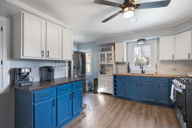 kitchen featuring appliances with stainless steel finishes, blue cabinets, white cabinetry, wood-type flooring, and sink