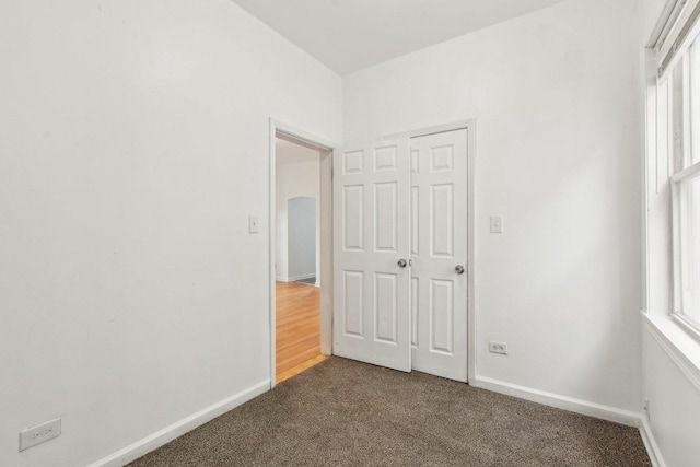 unfurnished bedroom with dark colored carpet and a closet