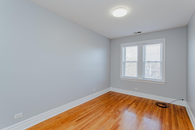 spare room featuring light wood finished floors, baseboards, and visible vents