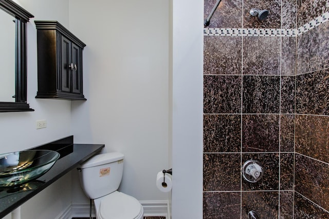full bath with toilet, visible vents, a sink, and a tile shower