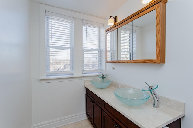 bathroom featuring double vanity, baseboards, and a sink