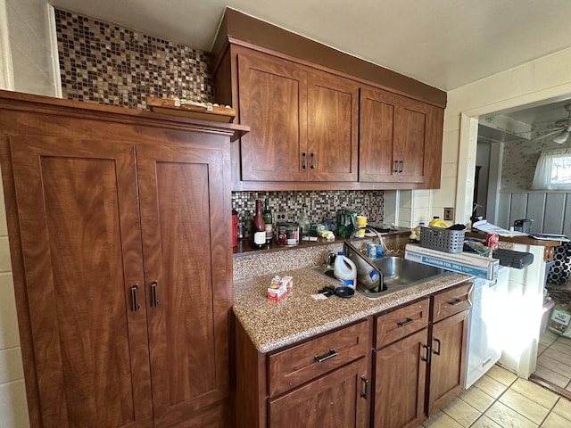 kitchen with light tile patterned floors, decorative backsplash, light stone countertops, and sink