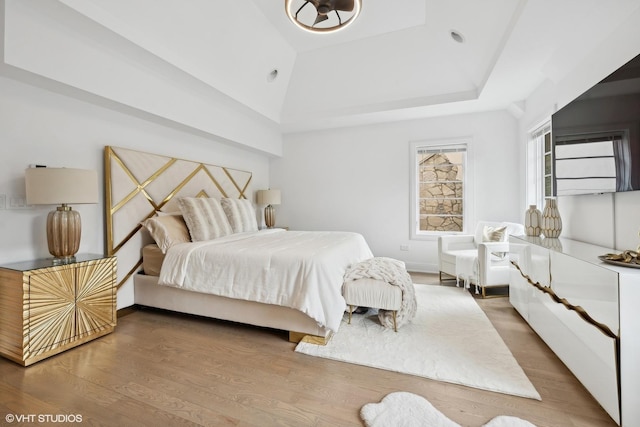 bedroom featuring a raised ceiling and hardwood / wood-style flooring