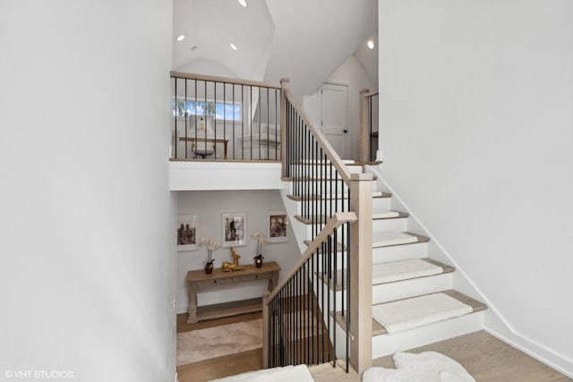 stairs with vaulted ceiling and wood-type flooring