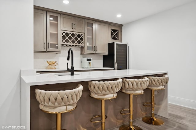 bar with hardwood / wood-style flooring, black refrigerator, and sink