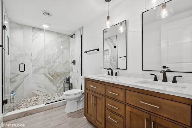 bathroom with a shower with shower door, vanity, and toilet