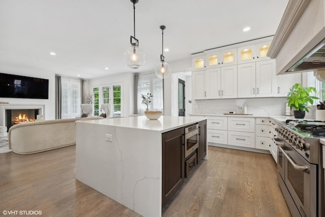 kitchen featuring premium range hood, a kitchen island, light wood-type flooring, stainless steel appliances, and white cabinets