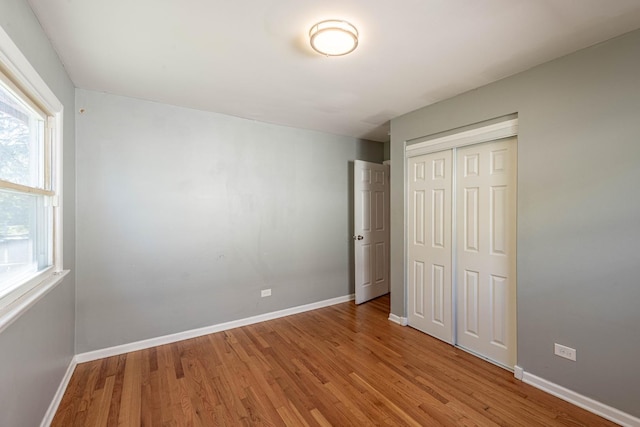 unfurnished bedroom featuring a closet, multiple windows, and hardwood / wood-style flooring