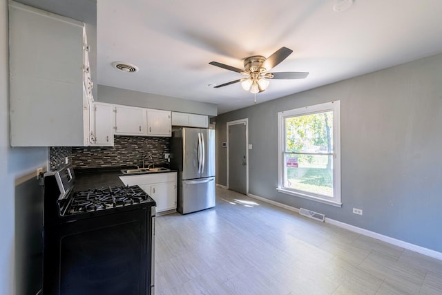 kitchen with white cabinetry, stainless steel appliances, decorative backsplash, sink, and ceiling fan