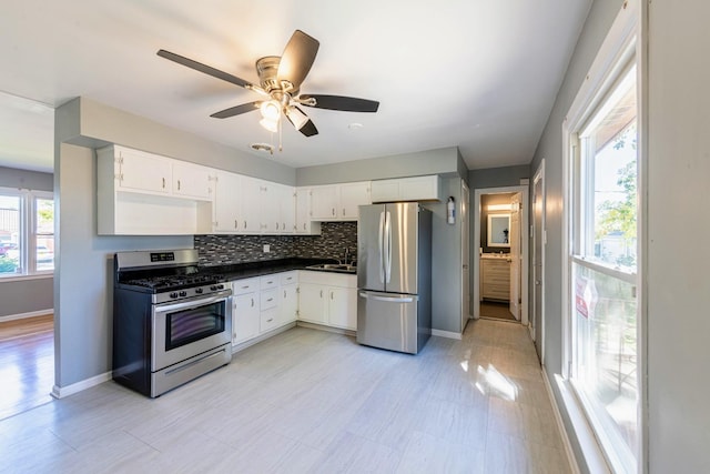 kitchen featuring white cabinetry, stainless steel appliances, sink, backsplash, and ceiling fan