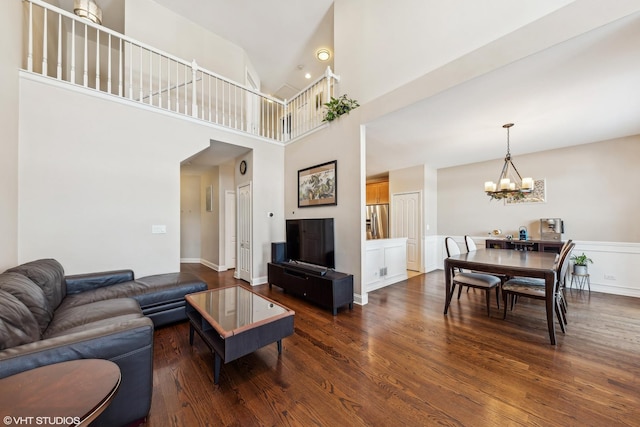 living room featuring a notable chandelier, a high ceiling, and dark wood-type flooring