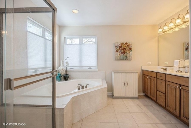 bathroom with tile patterned flooring, vanity, and a relaxing tiled tub