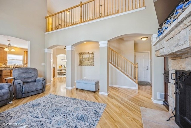 living room featuring hardwood / wood-style flooring, sink, a towering ceiling, and a fireplace