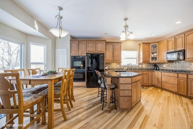 kitchen featuring hanging light fixtures, a center island, black appliances, and decorative backsplash