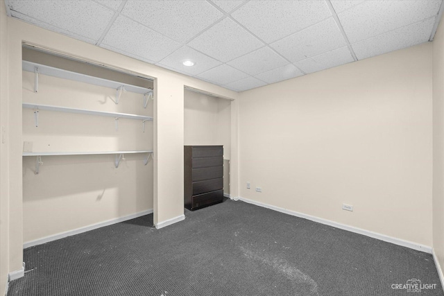 unfurnished bedroom featuring dark colored carpet and a paneled ceiling