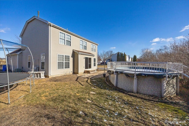 rear view of property featuring a trampoline and a yard