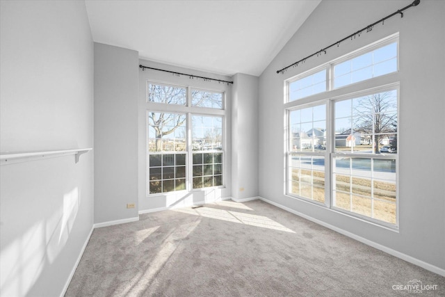 carpeted empty room with vaulted ceiling and a wealth of natural light