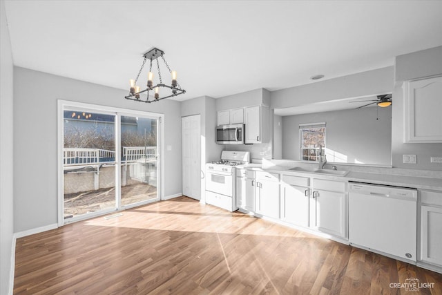 kitchen with decorative light fixtures, sink, white cabinets, and white appliances