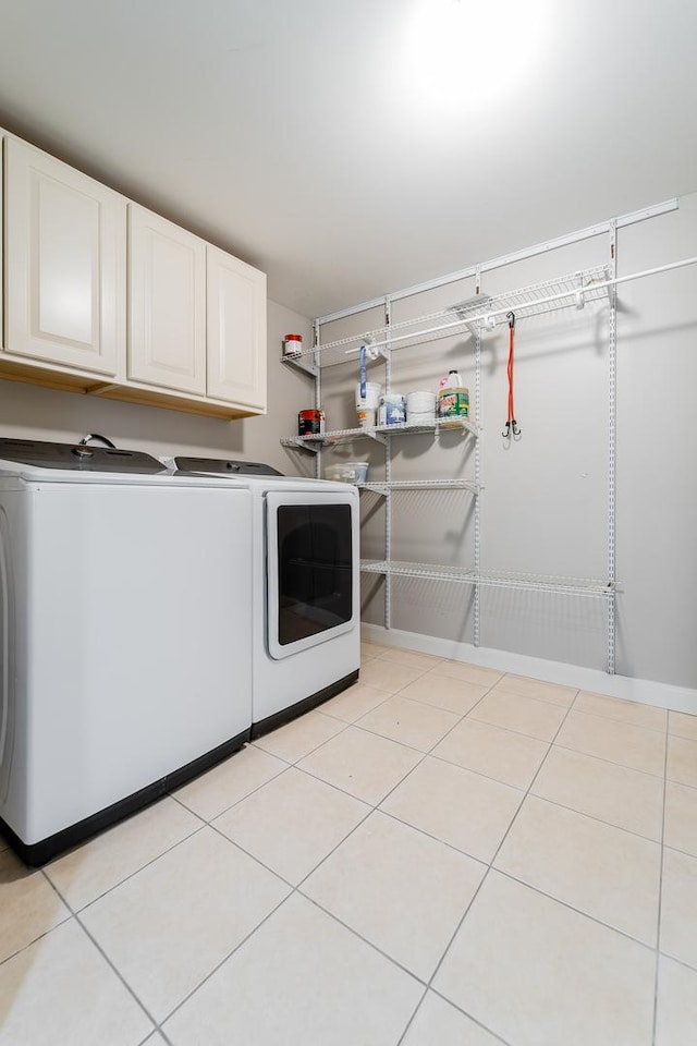 washroom with washer and clothes dryer, light tile patterned floors, and cabinets