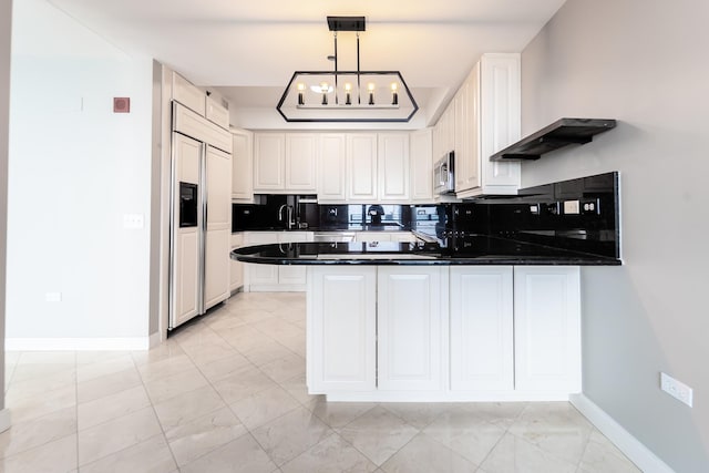 kitchen with paneled fridge, hanging light fixtures, and white cabinetry