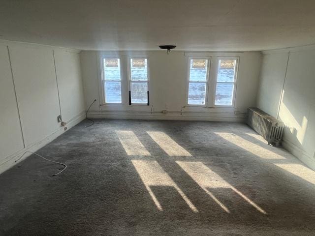 spare room featuring dark carpet and radiator