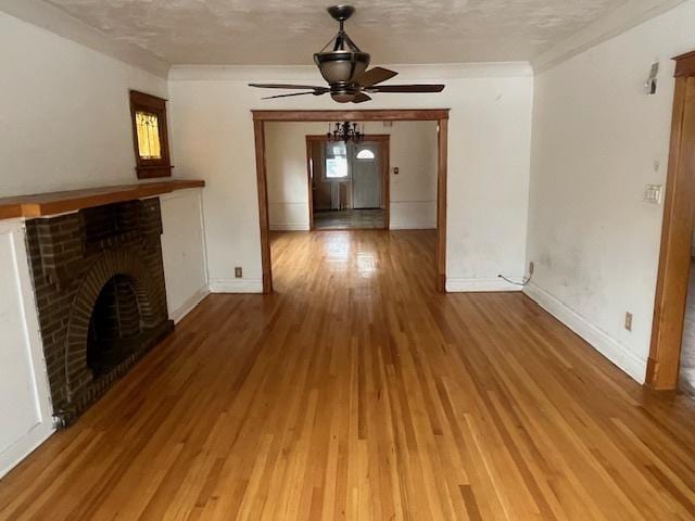 unfurnished living room with a textured ceiling, a fireplace, hardwood / wood-style flooring, ornamental molding, and ceiling fan