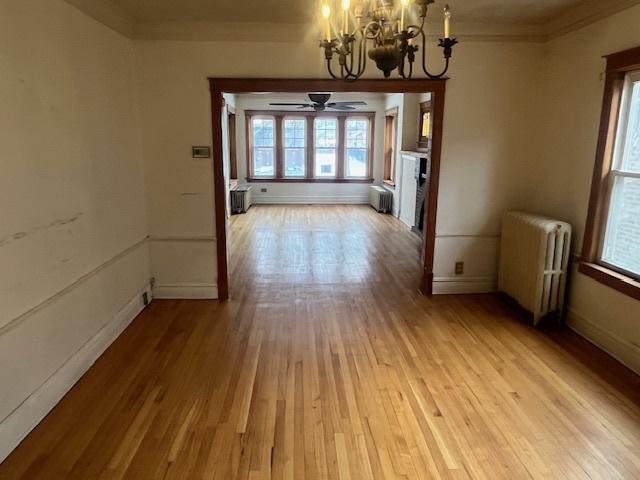 unfurnished dining area featuring radiator, a chandelier, and light hardwood / wood-style flooring