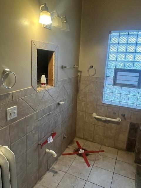 bathroom with tile walls, tile patterned floors, and radiator heating unit