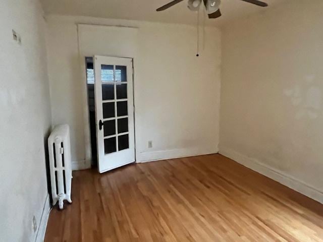 empty room featuring radiator, ceiling fan, and wood-type flooring