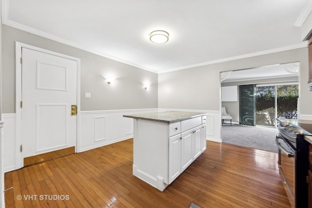 kitchen featuring stainless steel range with electric stovetop, white cabinetry, hardwood / wood-style flooring, light stone countertops, and a center island