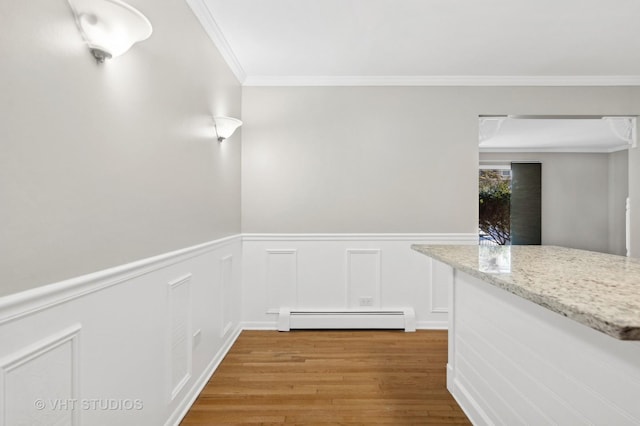 interior space featuring light wood-type flooring, baseboard heating, and crown molding