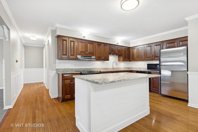 kitchen featuring crown molding, stainless steel appliances, a kitchen island, and light wood-type flooring