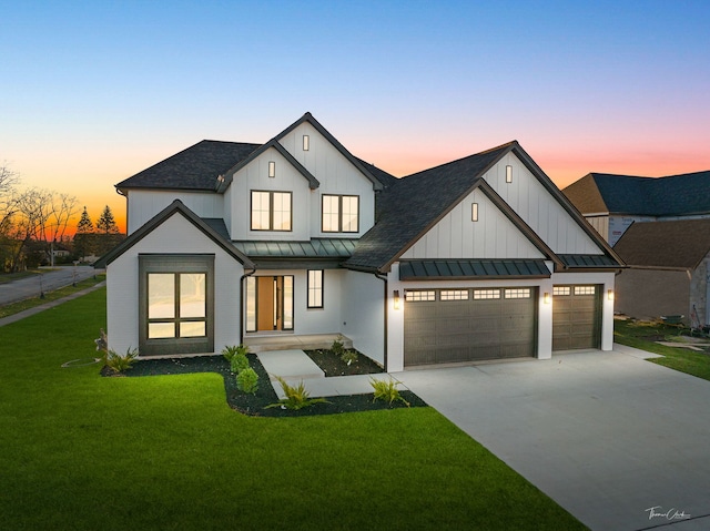 modern inspired farmhouse featuring a garage and a lawn