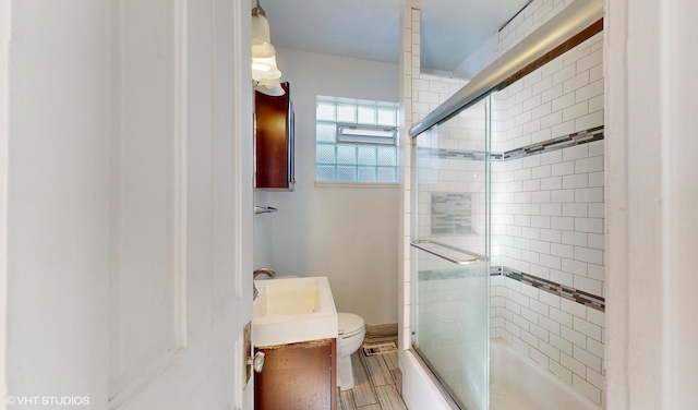 full bathroom featuring toilet, bath / shower combo with glass door, and vanity