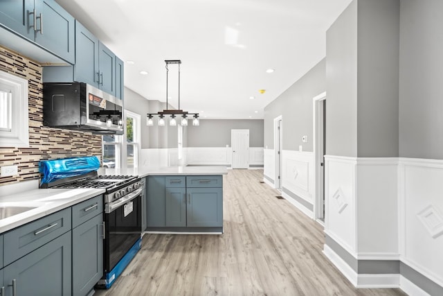 kitchen featuring decorative light fixtures, backsplash, light hardwood / wood-style floors, kitchen peninsula, and appliances with stainless steel finishes